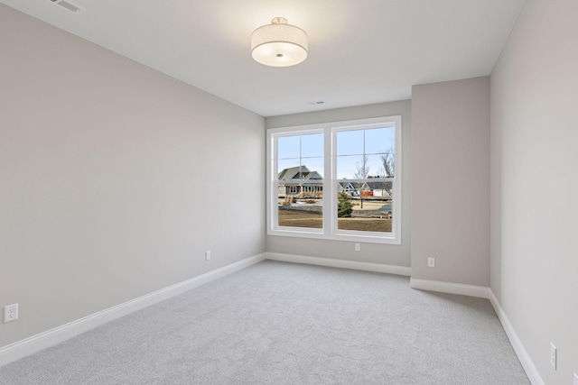 spare room with light carpet and baseboards