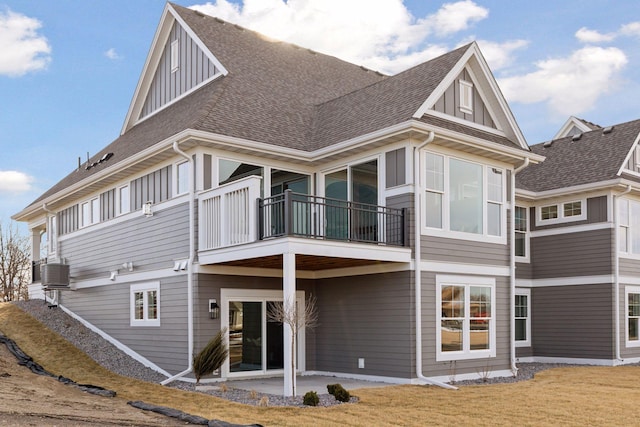 back of house with a patio area, board and batten siding, central AC, and roof with shingles