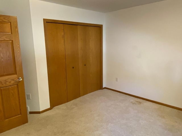 unfurnished bedroom featuring light carpet and a closet