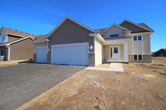 view of front of home featuring brick siding, driveway, a garage, and roof with shingles