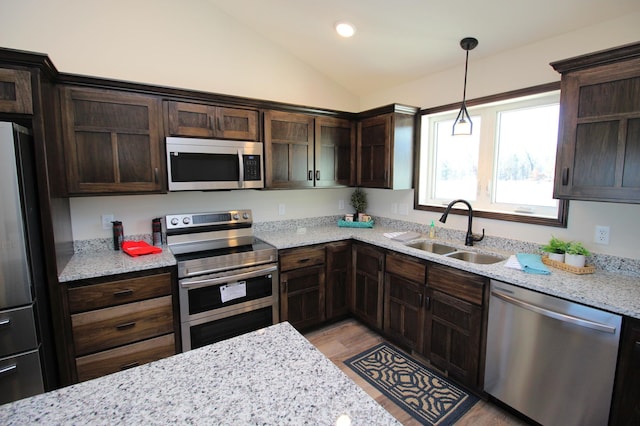 kitchen with vaulted ceiling, dark brown cabinets, appliances with stainless steel finishes, and a sink