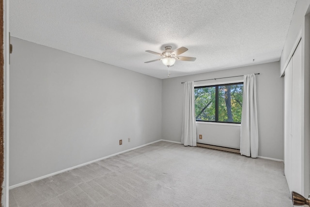 spare room featuring light carpet, ceiling fan, a baseboard heating unit, and a textured ceiling