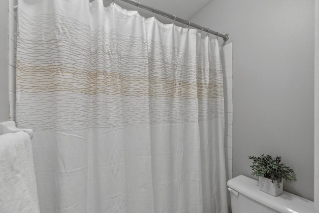 bathroom featuring a shower with shower curtain and toilet