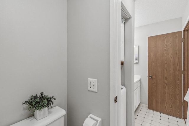 bathroom with vanity, tile patterned flooring, toilet, and a textured ceiling