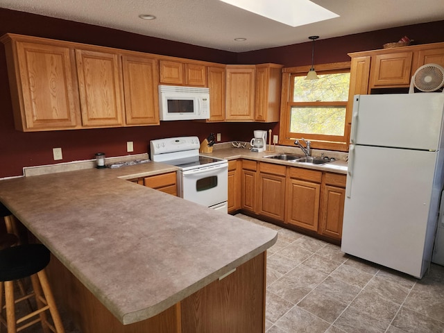 kitchen featuring pendant lighting, a peninsula, white appliances, a sink, and a skylight