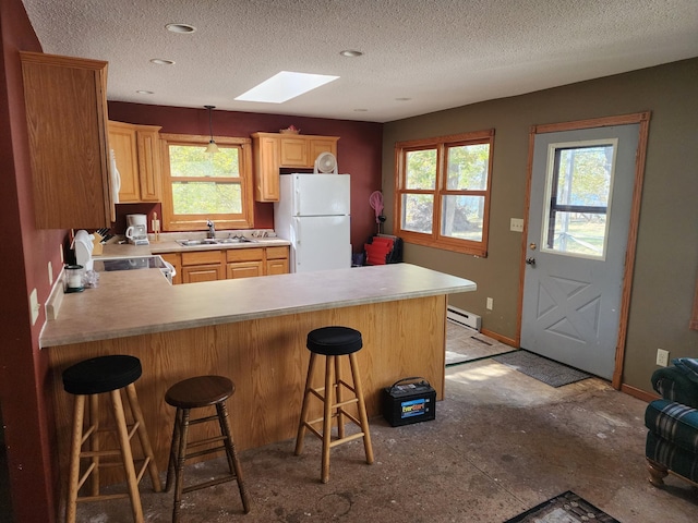 kitchen with a sink, white appliances, a peninsula, a baseboard radiator, and a skylight