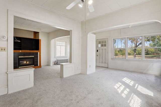 unfurnished living room with light carpet, a wealth of natural light, and radiator