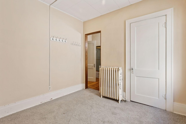 carpeted spare room featuring radiator heating unit