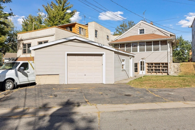 view of front of property featuring a garage, a sunroom, and a front lawn