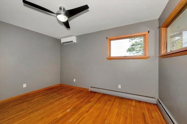 empty room with a baseboard heating unit, a wall unit AC, and light hardwood / wood-style flooring