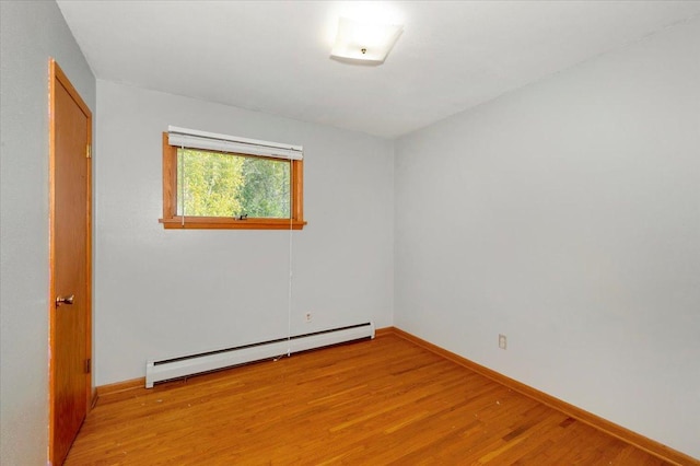 empty room featuring a baseboard radiator and light hardwood / wood-style floors