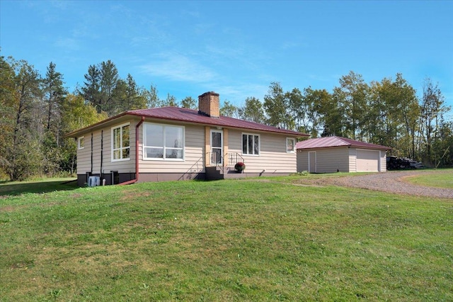 ranch-style home with a garage, an outbuilding, and a front lawn