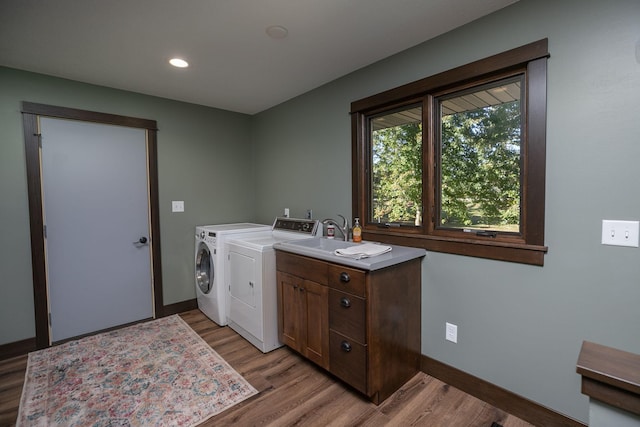 laundry room featuring light hardwood / wood-style flooring, washing machine and dryer, cabinets, and sink