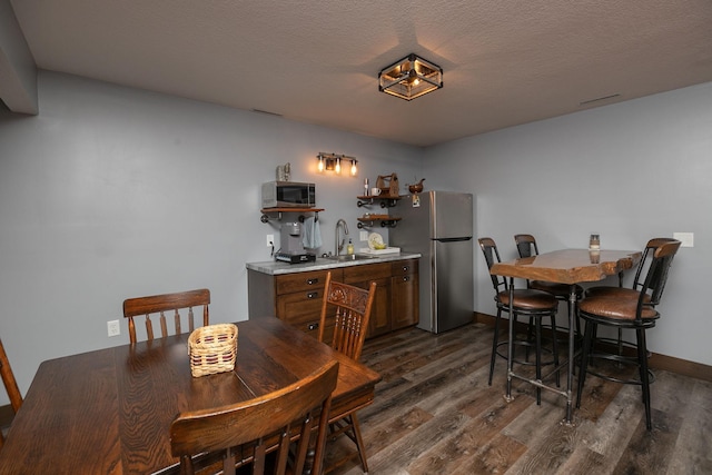 dining area featuring a textured ceiling, indoor wet bar, and dark hardwood / wood-style flooring