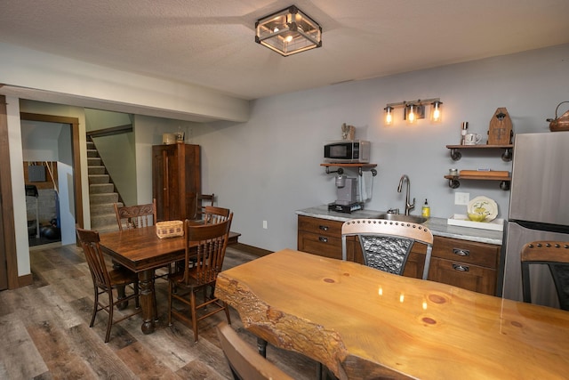 dining space featuring wood-type flooring, a textured ceiling, and sink