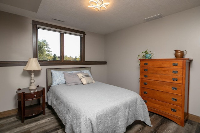 bedroom with dark hardwood / wood-style flooring and a textured ceiling