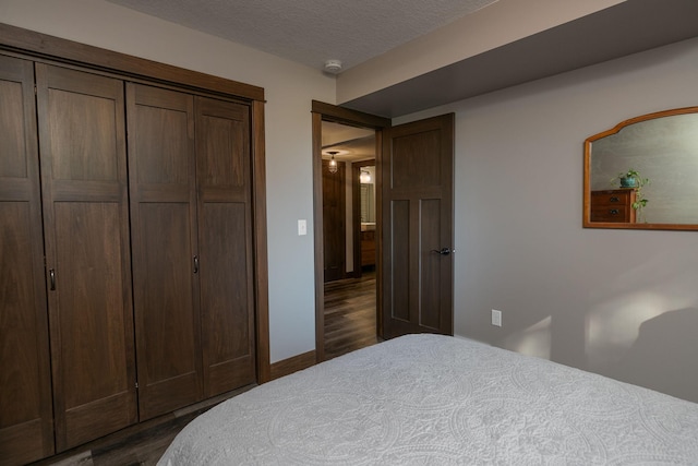 bedroom featuring dark wood-type flooring, a closet, and a textured ceiling