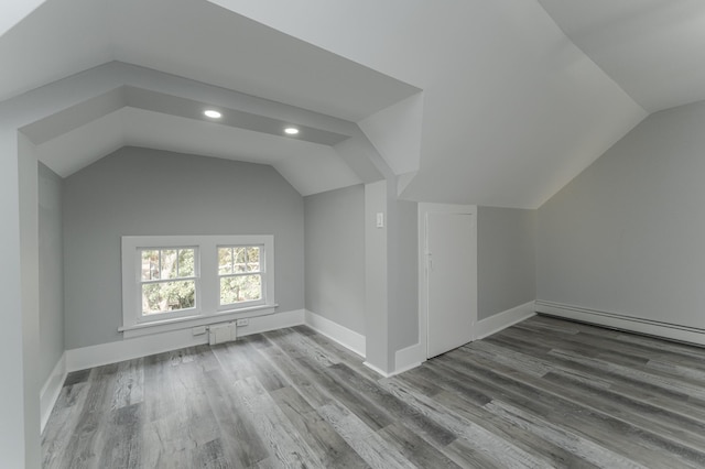 additional living space featuring vaulted ceiling, a baseboard radiator, and hardwood / wood-style floors