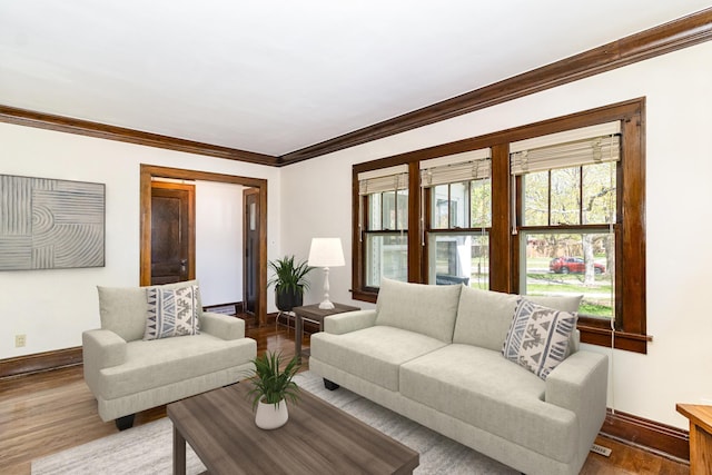 living room with baseboards, crown molding, and wood finished floors