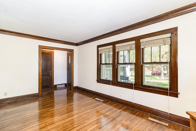 spare room with ornamental molding, baseboards, and light wood-type flooring