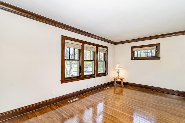 unfurnished room with baseboards, crown molding, and hardwood / wood-style floors