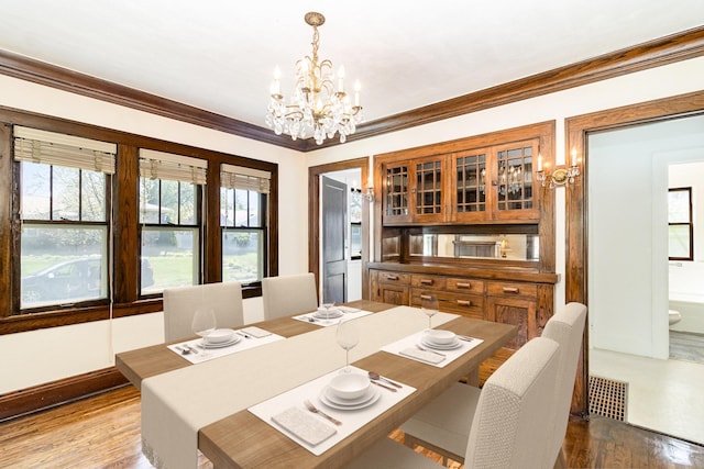 dining room with a chandelier, wood finished floors, and ornamental molding