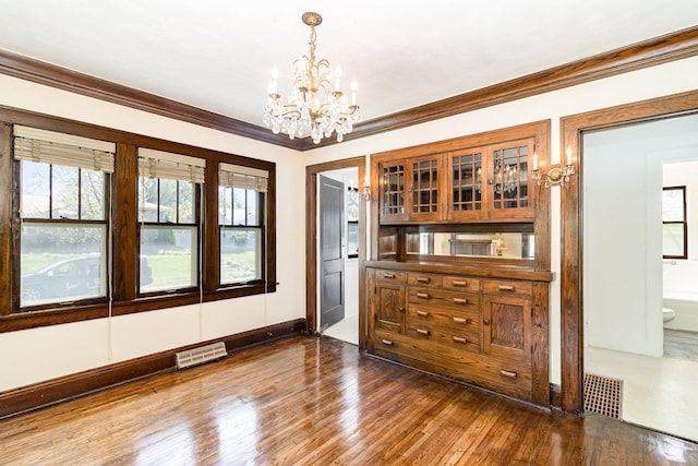 dining room with a chandelier, dark wood-style floors, crown molding, and baseboards