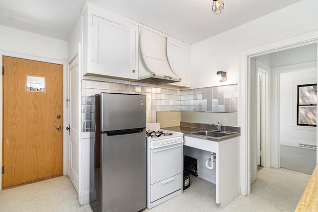 kitchen with freestanding refrigerator, stainless steel counters, ventilation hood, a sink, and white range with gas cooktop