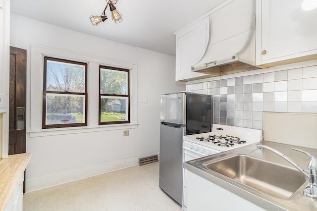 kitchen featuring a sink, tasteful backsplash, exhaust hood, and white cabinetry