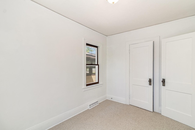 spare room featuring light carpet and baseboards