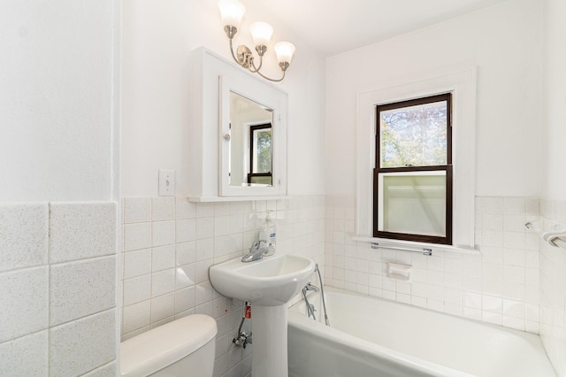 full bathroom featuring toilet, tile walls, a tub, and wainscoting