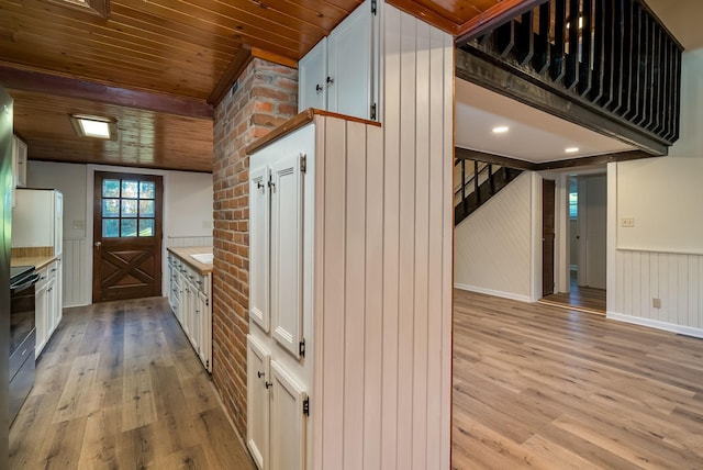 kitchen with light wood-type flooring, black electric range oven, wood ceiling, and white cabinets