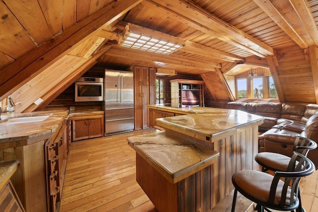 interior space featuring appliances with stainless steel finishes, wood walls, wood ceiling, and light hardwood / wood-style flooring