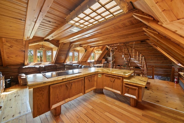 kitchen with vaulted ceiling with beams, wood ceiling, wooden walls, black electric stovetop, and light hardwood / wood-style floors