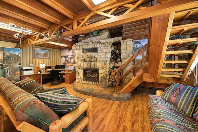 living room featuring hardwood / wood-style flooring, beamed ceiling, and a stone fireplace