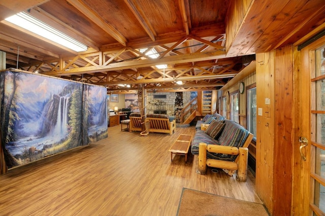 living room with wood ceiling, wood finished floors, and a stone fireplace