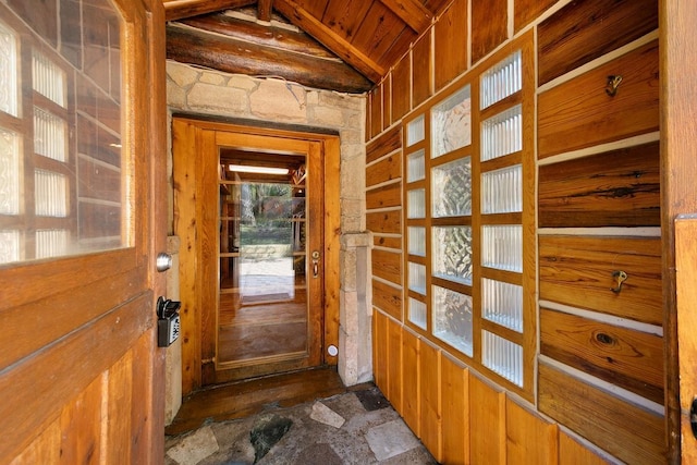 doorway to outside featuring wood walls and vaulted ceiling