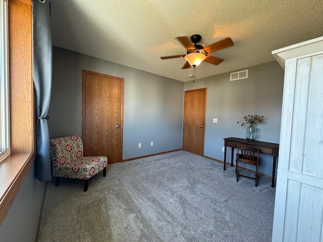 living area with a textured ceiling, carpet floors, and ceiling fan