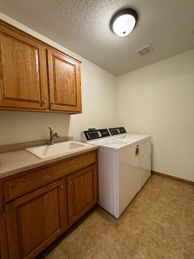 laundry area featuring separate washer and dryer, light tile patterned floors, a textured ceiling, cabinets, and sink