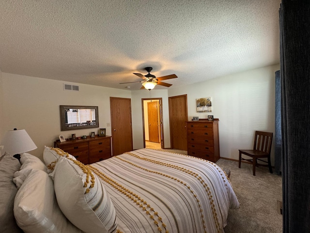 carpeted bedroom featuring ceiling fan and a textured ceiling