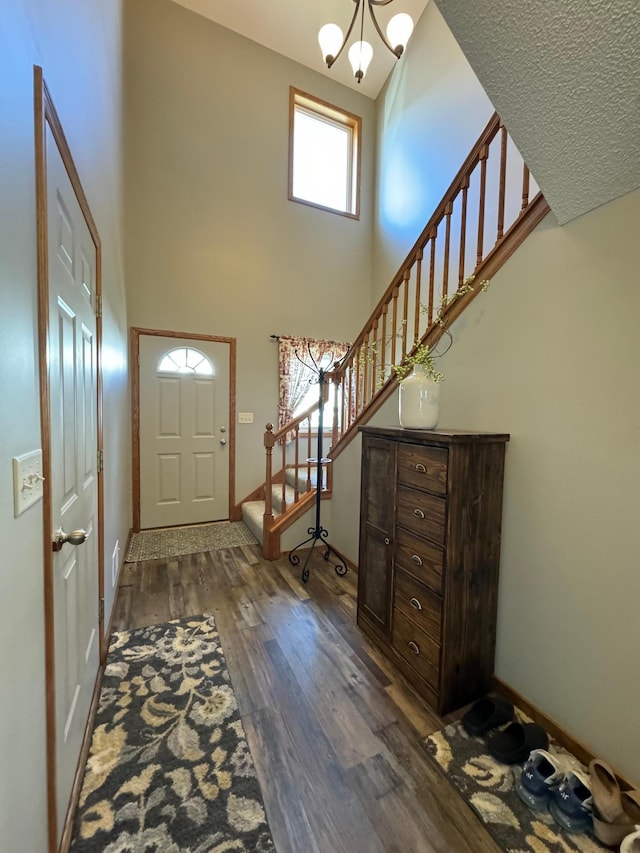 foyer entrance featuring a high ceiling, a chandelier, and dark wood-type flooring