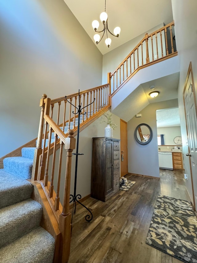 stairway featuring a notable chandelier, hardwood / wood-style floors, and high vaulted ceiling