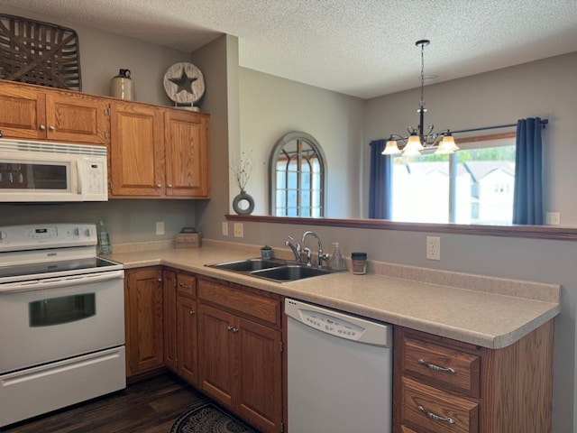 kitchen with white appliances, kitchen peninsula, dark hardwood / wood-style floors, sink, and a notable chandelier