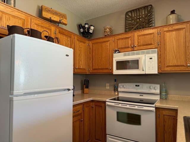 kitchen with a textured ceiling and white appliances