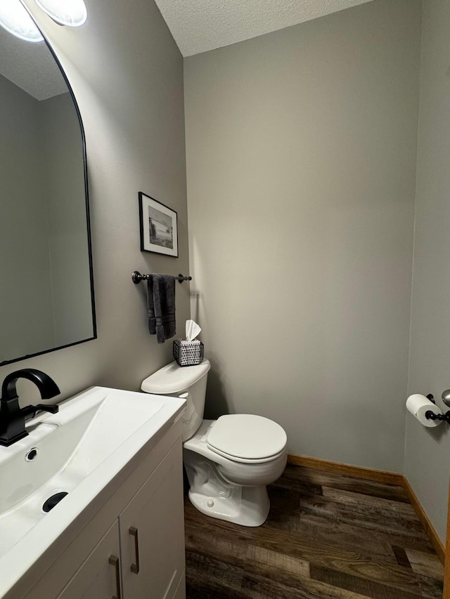 bathroom featuring wood-type flooring, a textured ceiling, vanity, and toilet