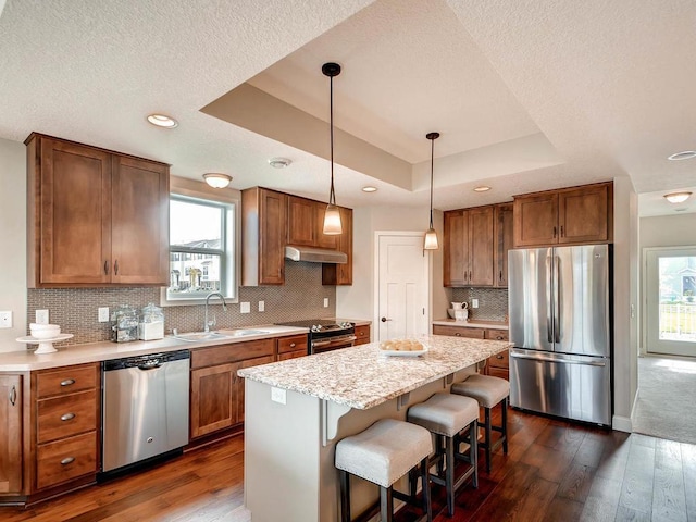 kitchen featuring stainless steel appliances, plenty of natural light, dark wood-type flooring, and a kitchen island