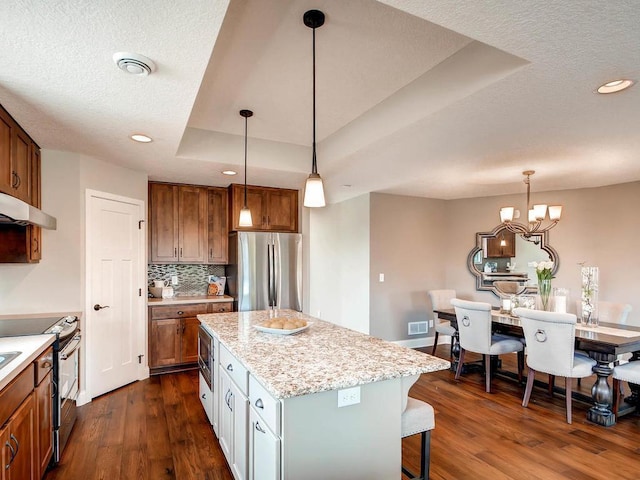 kitchen with stainless steel appliances, hanging light fixtures, dark hardwood / wood-style flooring, and a center island