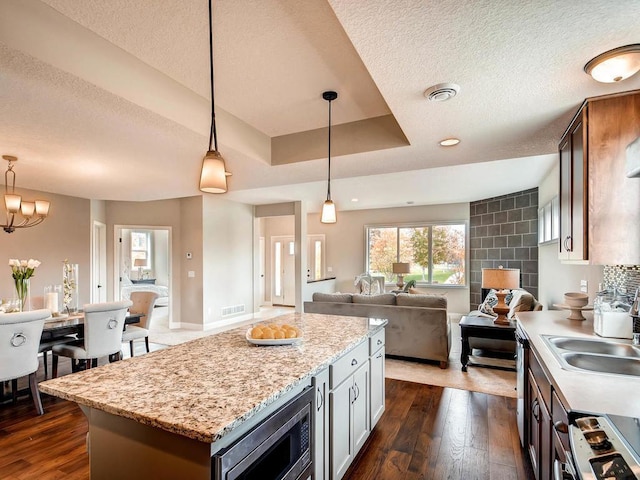 kitchen with a kitchen island, dark hardwood / wood-style flooring, sink, hanging light fixtures, and appliances with stainless steel finishes