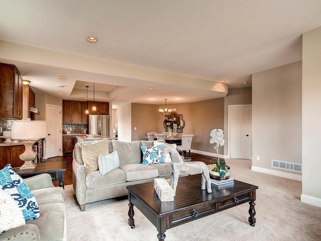 living room with light colored carpet and a notable chandelier