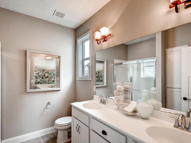 bathroom featuring toilet, wood-type flooring, an enclosed shower, vanity, and a textured ceiling